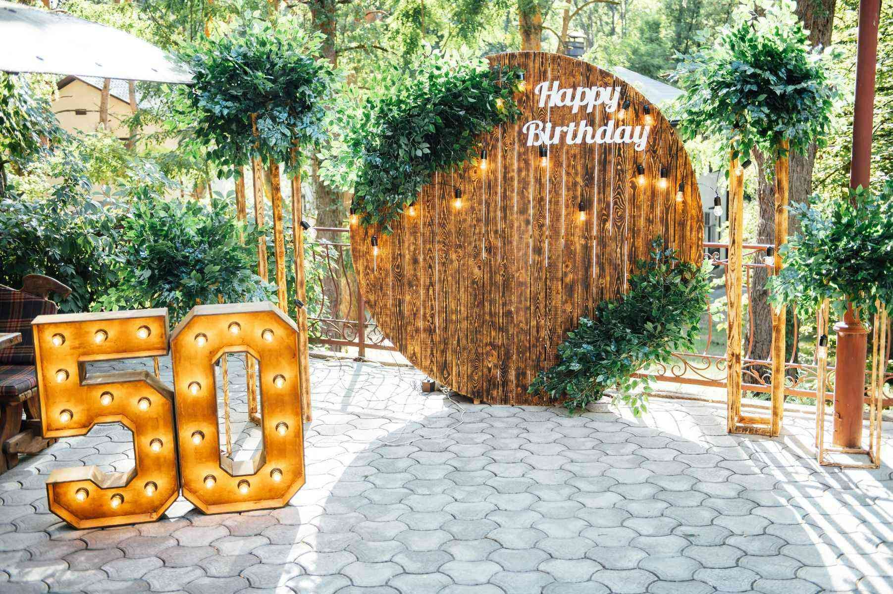 Fotografía exterior con un arco de madera en el que pone feliz cumpleaños y el número 50 al lado