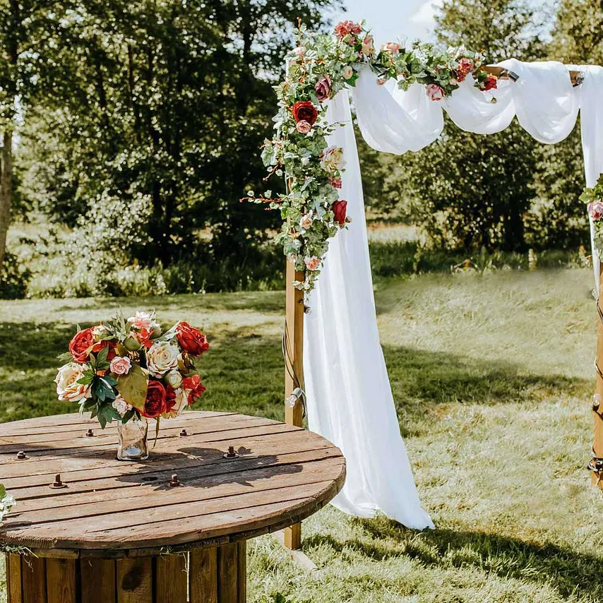 Fotografía de un jardín con un arco de boda y flores