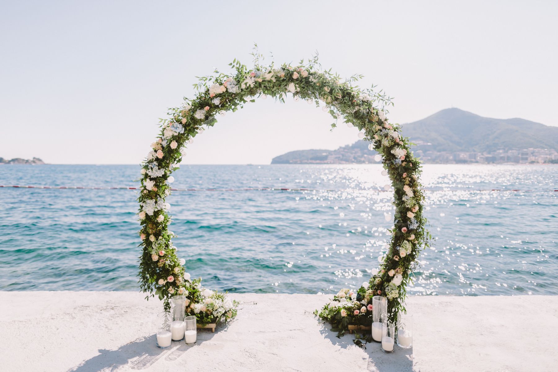 Fotografía de un arco de boda con flores al lado del mar